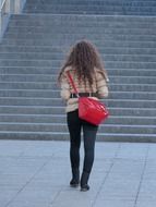 back view of young girl with red shopping bag at stairs