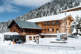 modern wooden buildings on forested mountain side at winter, austria