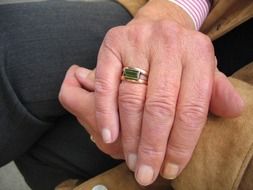 folded hands of old woman with gold ring on finger