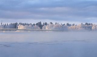 bridge across frozen river at forest, scenic winter landscape