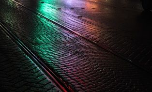 colorful illuminated wet railroad on street in city