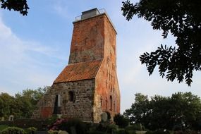 View from behind the trees to the old church with the bell tower