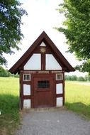 old small truss building on a meadow in countryside