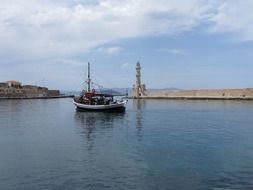 boat on sea in view of lighthouse, greece, crete, chania