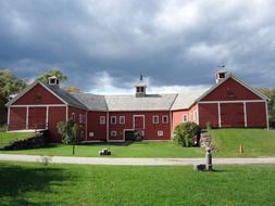 old red wooden farmhouse on green lawn under cloudy sky, usa, vermont