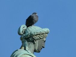 pigeon sits on head of bronze sculpture