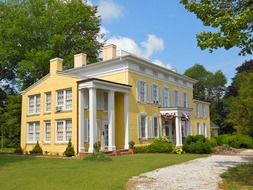 old yellow mansion with columns in summer park, usa, delaware