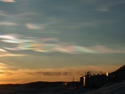 colorful nacreous clouds in evening sky above buildings