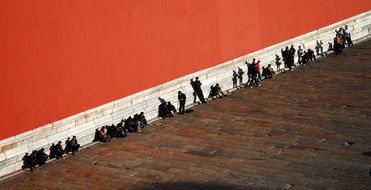 people resting at red wall of palace museum, china, beijing