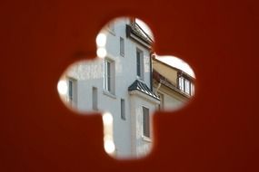 House facade through the hole in a red wall