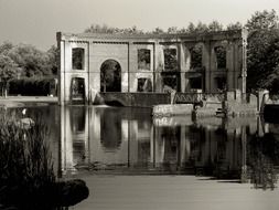 aged ruins at pond in summer park