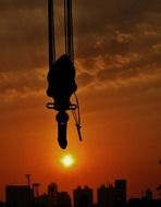 crane hook at sunset sky above city