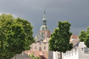 spire of St. Nicholas' Church at clouds among tile roofs of old town, germany, stralsund