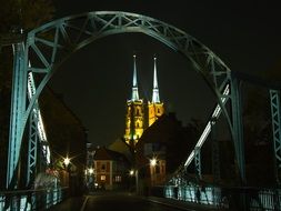 towers of cathedral in arch of bridge at night, poland, wroclaw