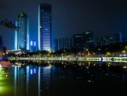 glowing night buildings of Chengdu and their reflection in the river, China