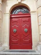 old wooden red door under arched window