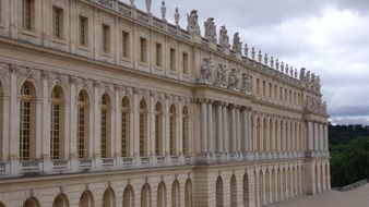 Palace side with statues on top at clouds in france in versailles