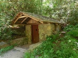 small stone building with wooden roof among trees