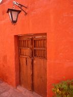 Wooden door of red home with a lantern
