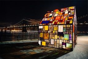 illuminated stained glass cabin on embankment in winter night city, usa, new york