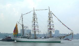 sailing ship with sailors on masts in view of city, usa, nyc