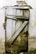 old wooden door in damaged wall