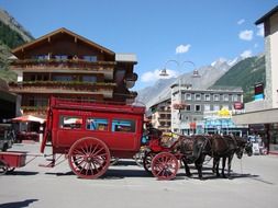 red vintage horsedrawn carriage on plaza in village at mountains, switzerland, zermatt