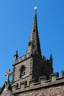 gothic church spire and cross at blue sky, uk, england, leicester, hinckley