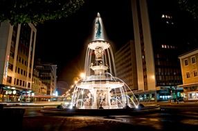 beautiful illuminated Grande Fontaine in city at night, switzerland, la Chaux-de-Fonds