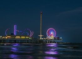 colorful night city skyline with ferris wheel in amusements park, usa, texas, galveston