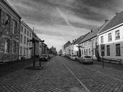 black and white photo of a road with cars near buildings