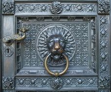 bronze lion head, knocker, on ornate entrance door of cologne cathedral, germany