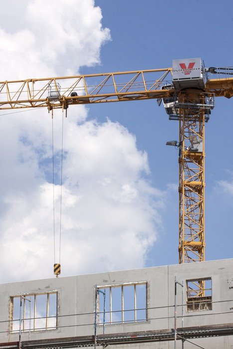 Yellow construction crane against the sky with clouds