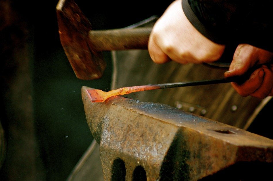 blacksmith at work, hands with hammer and iron