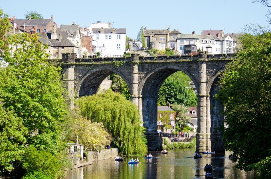 people in rowing boats on river under knaresborough bridge, uk, england