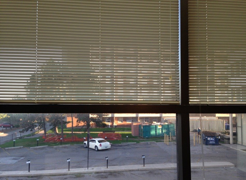 view of parking lot through window with blinds