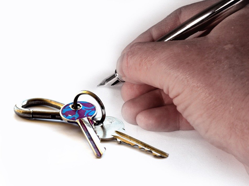 hand with pen and house keys at white background