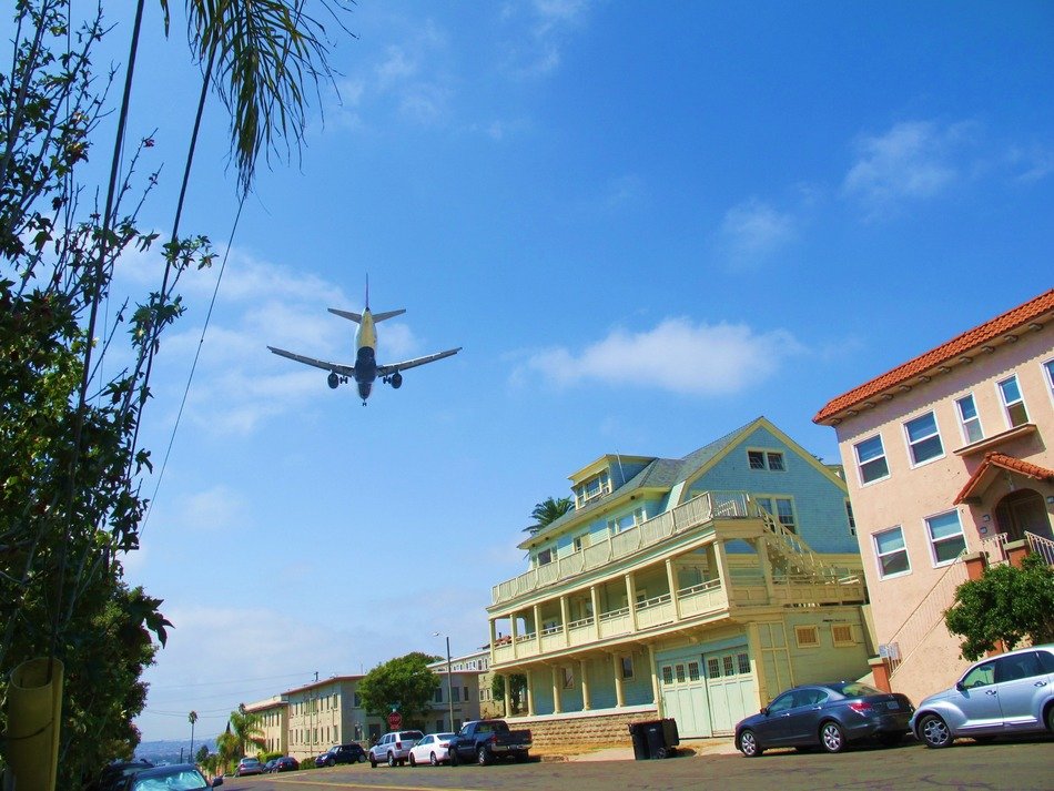 airplane in sky above colorful buildings at sea, usa, california, san diego