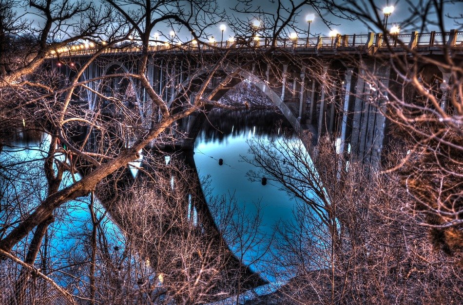 bridge with lanterns reflecting on water at night