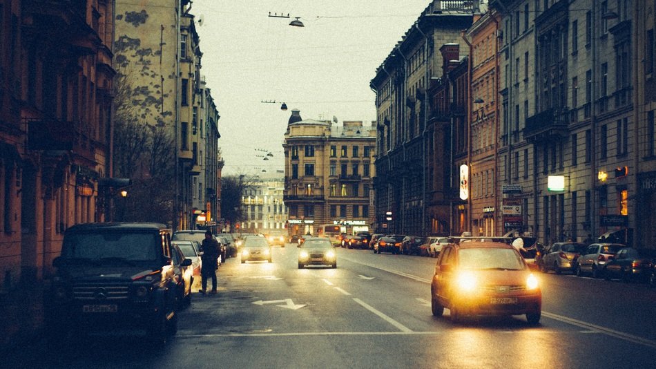 gars with bright headlights on street at twilight, russia, st petersburg
