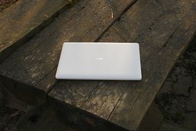 White laptop on a rough wooden surface