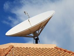 parabolic antenna on clay tile roof at sky