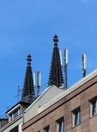 church spires behind building with antennas at top of roof, germany, cologne