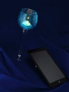 black smartphone and glass goblet