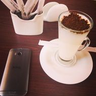 coffee with chocolate and a mobile phone on a table in a cafe