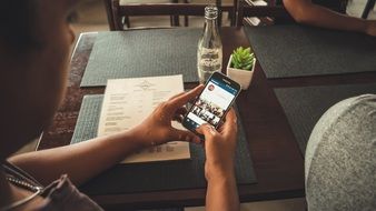 instagram user sits at table in cafe