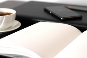 a cup of coffee, a mobile phone and an open notebook