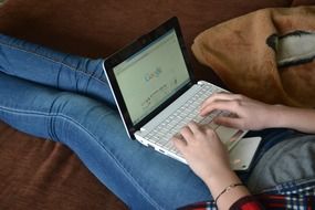 writing on a laptop, which is on his knees