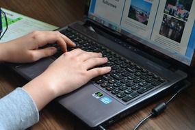 writing on a laptop, which is on the table