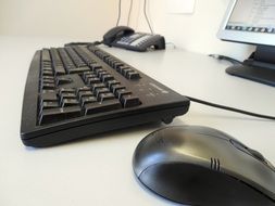 Black mouse and keyboard near the computer